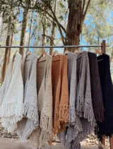 Ruana tejida a mano en lana Merino hilado grueso, con diseño en V y flecos.