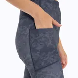 Calza deportiva de tiro medio con estampado camuflado en tonos azules y grises. Presenta un ajuste ceñido al cuerpo, costuras reforzadas y el logo de la marca estampado en la pierna izquierda.