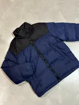 Campera puffer azul con canesú negro y cierre frontal.