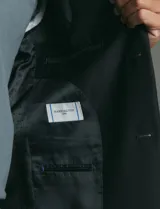 Traje de corte clásico compuesto por saco de dos botones con solapas tradicionales y pantalón de vestir a juego. Confeccionado en tejido liso de poliéster.