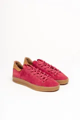 Zapatilla de cuero vacuno color rojo, con cordones al tono y suela de caucho color caramelo. Detalle de cuero vacuno color tostado en el talón.