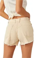Short de denim color beige, de tiro medio con bolsillos delanteros y traseros. Presenta roturas sutiles en la parte delantera y dobladillo desmechado.