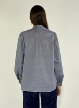 Camisa color beige con cuello mao, mangas largas abullonadas y cierre frontal con botones.