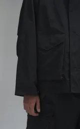 Campera técnica liviana de microfibra negra con acabado mate, capucha ajustable, cierre frontal oculto bajo solapa, bolsillos frontales con solapa y cordón ajustable en la cintura.
