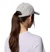 Gorra Columbia Twin Canyon Ball Cap color gris, con visera curva, ojales bordados para ventilación y un parche frontal cuadrado con el logo de la marca en negro, amarillo, marrón y blanco.