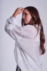 Camisa negra de tela traslúcida con cuello clásico, cierre frontal con botones y dos bolsillos de parche en el pecho.