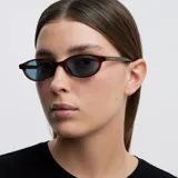 Lentes de sol con montura ovalada de acetato en color mostaza y cristales polarizados en tono celeste.