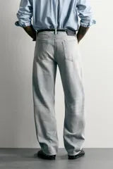Pantalón denim de corte recto desde la cadera hasta el tobillo, de tiro medio y color celeste claro con efecto lavado. Cuenta con diseño clásico de cinco bolsillos y cierre frontal con cremallera y botón metálico.