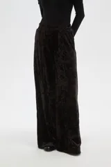 Pantalon de corte ancho y tiro alto, confeccionado en tela de terciopelo con acabado brillante. Presenta cintura elástica y pinzas frontales que aportan volumen y caída fluida a la prenda.