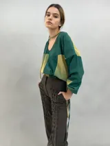Pantalón tipo babucha confeccionado en lana de oveja, color visón. Presenta un diseño de tiro alto con textura vertical plisada a lo largo de las piernas, cintura con cierre de doble broche y puños elásticos en los tobillos.