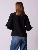 Blusa de gasa estampada con flores azules y violetas sobre fondo blanco, de manga 3/4 con volados.