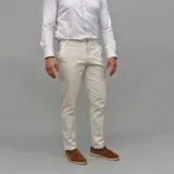 Pantalón de gabardina color beige claro, de corte ajustado y tiro medio, con cierre frontal y bolsillos laterales.
