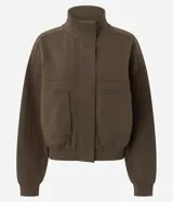 Campera marrón estilo bomber, confeccionada en punto roma, con cuello alto, mangas largas, cierre frontal oculto, bolsillos frontales aplicados y recortes en el pecho.