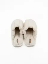 Pantuflas de estar por casa tipo chinela, confeccionadas en tela de peluche suave color crudo, con diseño acolchado de franjas verticales y suela plana.