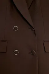 Blazer blanco de manga larga con cuello solapa y hombreras. Diseño cruzado con cierre frontal de cuatro botones y bolsillos delanteros con solapa.