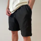 Short de algodón rústico color negro, de corte oversize, con bolsillos laterales y cintura elástica con cordón de ajuste.