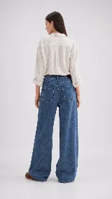 Pantalón de jean color naranja con tiro medio, diseño de pierna ancha y cinco bolsillos. Presenta costuras con pespuntes a contratono.