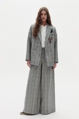 Blazer gris con estampado de cuadros, de doble botonadura, bolsillos delanteros y solapas de muesca. Viene decorado con múltiples pins metálicos en ambas solapas y un pañuelo estampado en el bolsillo del pecho.