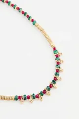 Collar corto con cuentas de metal dorado y cuentas de vidrio azul oscuro, con detalles de pequeñas borlas doradas en la parte frontal.