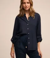 Camisa de manga larga color azul marino, con cuello camisero y botonadura frontal. Presenta un calce holgado y puños ajustables con botón.