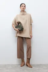 Sweater oversized color beige con cuello alto y cierre frontal corto. Presenta mangas cortas y un corte holgado.