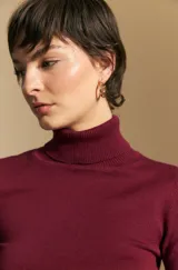 Polera de tejido fino color negro, con cuello alto y mangas largas con terminación sutilmente fruncida. Diseño ajustado al cuerpo.