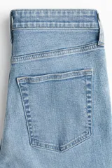 Jean de tiro alto con corte acampanado desde la rodilla y bajo deshilachado. Presenta diseño clásico de cinco bolsillos, cierre frontal con botón y costuras reforzadas en el ruedo.