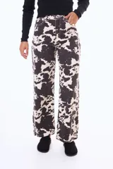 Jean de corte recto y tiro alto con estampado animal print tipo vaca en blanco y negro. Cuenta con cierre frontal, botón metálico y bolsillos laterales y traseros.