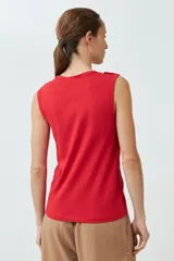 Musculosa de algodón color rojo, con cuello redondo, corte sin mangas y detalle de botones decorativos en los hombros.