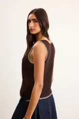 Musculosa de punto color blanco crudo, con escote en V y terminaciones con bordado artesanal amarillo.