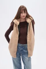 Chaleco sin mangas de pelo sintético color beige claro, con capucha y cierre frontal.