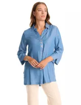 Blusa de lyocell en tono azul denim, con cuello camisero, escote en V y cierre frontal parcial con botones. Presenta mangas tres cuartos amplias y un corte holgado.
