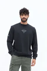 Buzo de algodón color negro lavado, con cuello redondo y estampado frontal en blanco con texto que incluye "BROOKSFIELD COVENT GARDEN LON UK". Presenta un pequeño parche negro en la manga izquierda.