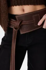 Faja ancha de cuero marrón chocolate con costuras decorativas contrastantes, cierre de nudo envolvente y trabilla lateral. Lleva la marca Petra grabada.