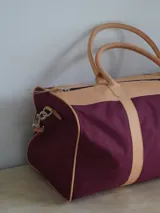 Bolso de lona color verde militar con detalles en cuero marrón. Tiene doble asa de mano y correa de hombro ajustable y extraíble.