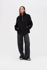 Buzo de sherpa con textura capitoneada, color bordó, con cuello alto y cierre frontal parcial. Presenta bolsillos laterales y calce relajado.