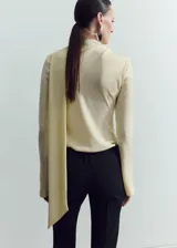 Blusa de manga larga color amarillo claro, con cuello alzado y detalle de abertura asimétrica en el escote.