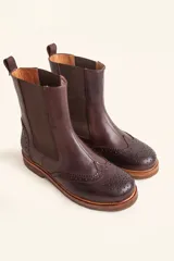 Bota tipo Chelsea de cuero vacuno color suela, con diseño brogue en la puntera y laterales. Presenta paneles elásticos laterales en color marrón oscuro, tirador trasero y suela de goma con plataforma.