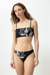 Bombacha de bikini tiro medio color negro con bordado de flores blancas.