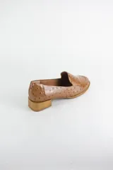 Mocasin de cuero con textura símil avestruz en color suela, con punta redonda y taco bajo cuadrado símil madera.