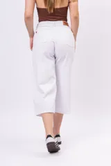 Pantalón capri de denim rígido en color blanco, de tiro alto y pierna amplia con largo al tobillo.
