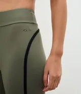 Legging deportivo de tiro alto en color verde oliva, con costuras laterales en contraste negro. Confeccionado en tejido de microfibra elástica, ofrece un ajuste ceñido y cómodo para actividades físicas.