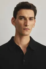 Remera polo de manga larga confeccionada en tejido de punto de lana merino, con cuello clásico, tapeta de botones frontal y terminaciones acanaladas en puños y bajo.