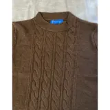 Buzo de punto blanco de manga larga con diseño trenzado y cuello redondo.