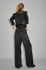 Jean de corte wide leg en color negro, con diseño de paneles laterales que crean un efecto de abertura o contraste en el bajo. Posee tiro medio y cierre clásico con botón y cremallera.