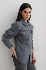 Chaqueta de denim color marrón, con corte entallado en la cintura, cierre frontal con botones metálicos y bolsillos superiores con solapa.