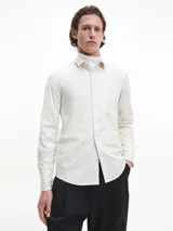 Camisa de manga larga color blanco hueso, de corte slim, con cuello tradicional y cierre frontal de botones.