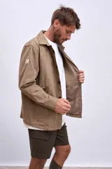 Cazadora color beige con cuello clásico, cierre frontal con botones, mangas largas y bolsillos de parche en el pecho.