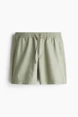 Short de lona de algodón color verde claro, con cintura elástica ajustable mediante cordón, bolsillos laterales al bies y un bolsillo insertado trasero.