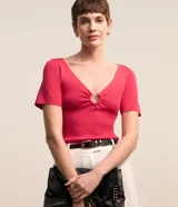 Blusa de punto color fucsia, de mangas cortas y escote en V con aro metálico.